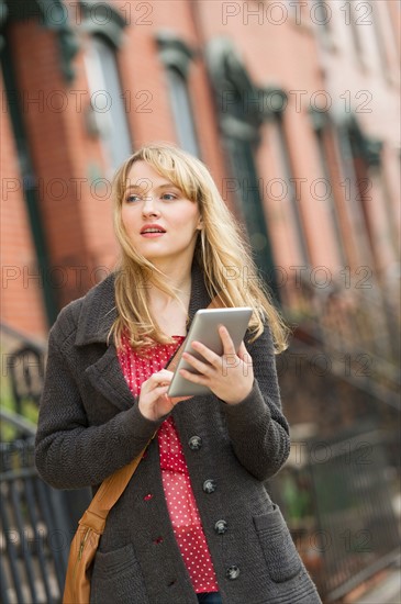 Woman using digital tablet on street.