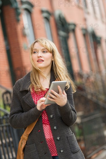 Woman using digital tablet on street.