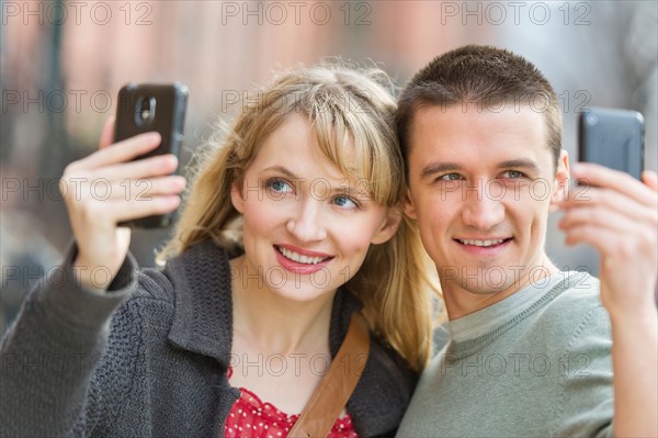 Couple photographing themselves with smart phones.