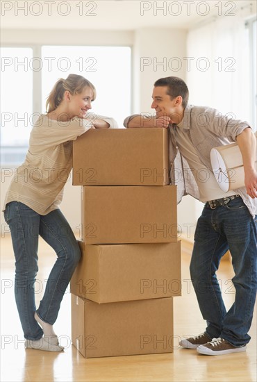 Couple leaning on cardboard boxes during relocation.