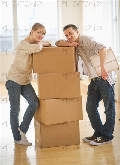 Couple leaning on cardboard boxes during relocation.