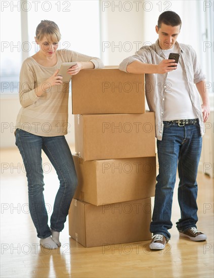 Couple leaning on cardboard boxes during relocation.
