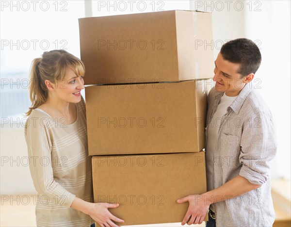 Couple carrying cardboard boxes during relocation.