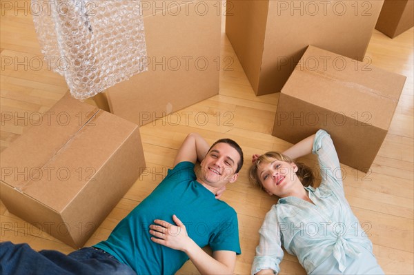 Couple lying among cardboard boxes during relocation.