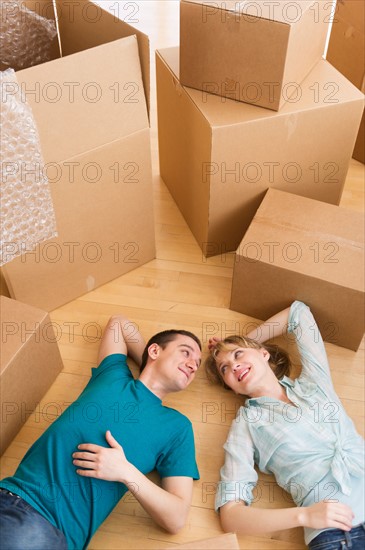 Couple lying among cardboard boxes during relocation.