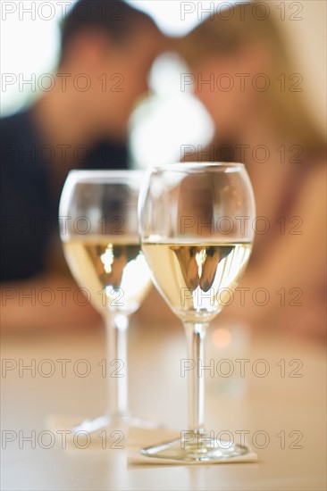 Close up of wine glasses with couple in background.