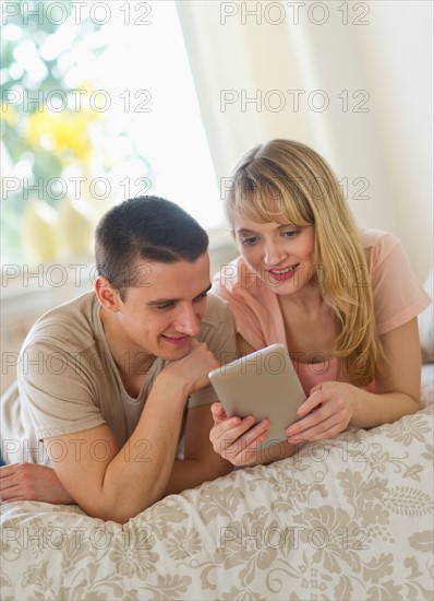 Couple lying on bed and using digital tablet.