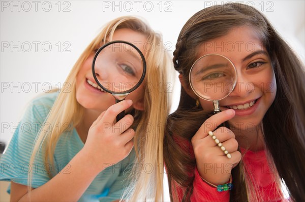 Two girls looking through magnifying glasses. Photo : Jamie Grill