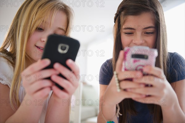 Two girls texting on smart phones. Photo : Jamie Grill