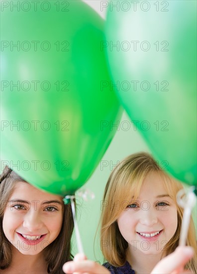 Two girls holding green balloons. Photo : Jamie Grill