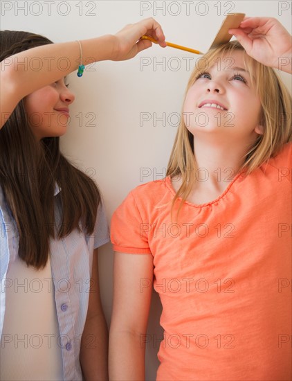 Two girls measuring height. Photo : Jamie Grill