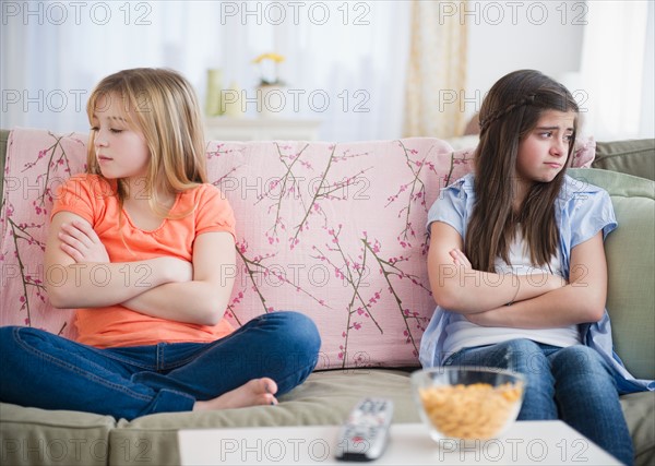 Two girls sitting on sofa and showing disgust. Photo : Jamie Grill