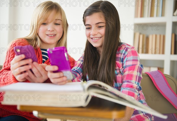 Two girls using mobile phones. Photo : Jamie Grill