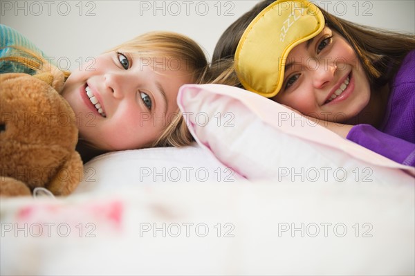 Two girls lying in bed. Photo : Jamie Grill