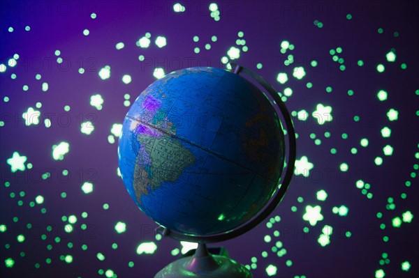 Fluorescent stars  and globe on blue background, studio shot. Photo : Jamie Grill