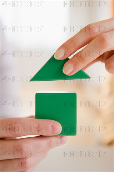 Close up of man's and woman's hands holding wooden blocks. Photo : Jamie Grill