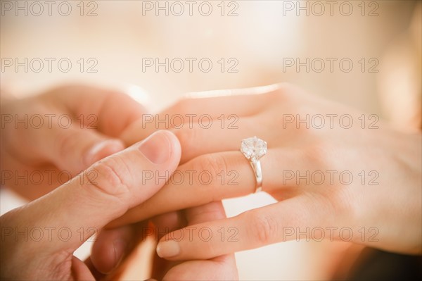 Close up of man's and woman's hands with engagement ring. Photo : Jamie Grill