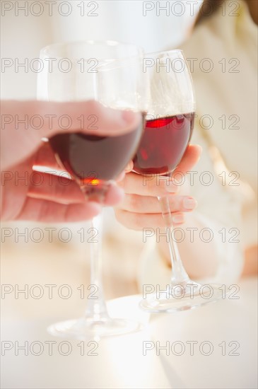 Close up of man's and woman's hands making toast with red wine. Photo : Jamie Grill