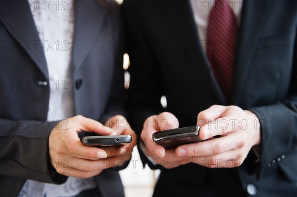 Close up of business people's hand texting on mobile phones. Photo : Jamie Grill