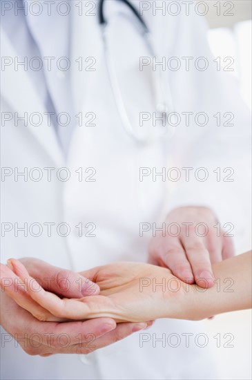 Close up of doctor taking patient's pulse. Photo : Jamie Grill