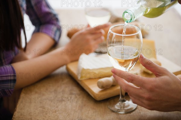 Close up of couple pouring wine and dining. Photo : Jamie Grill