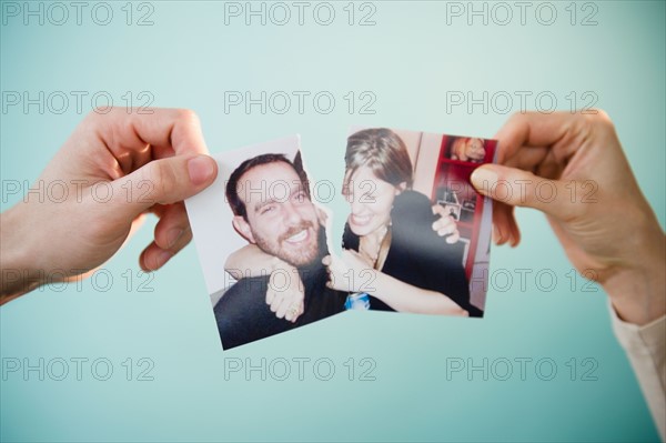 Close up of man's and woman's hands holding torn photograph of themselves,  studio shot. Photo : Jamie Grill