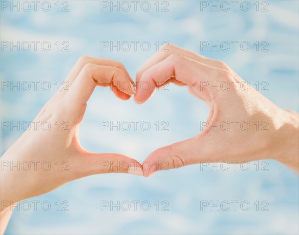 Close up of man's and woman's hands making heart shape, studio shot. Photo : Jamie Grill