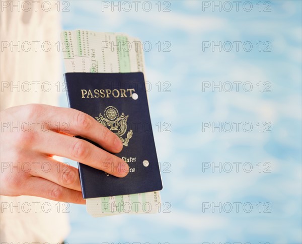 Close up of woman's hand holding passport, studio shot. Photo : Jamie Grill