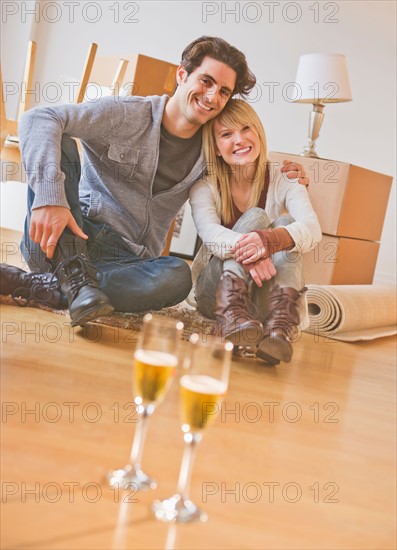 Close up of wine glasses on floor with couple behind. Photo : Daniel Grill