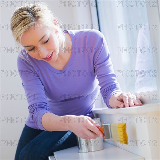 Woman painting window frame. Photo : Daniel Grill