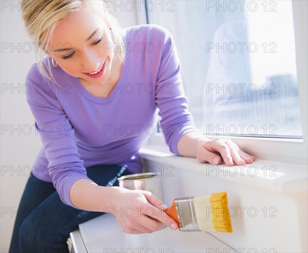 Woman painting window frame. Photo : Daniel Grill