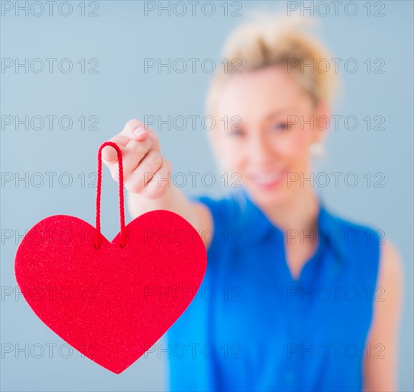 Close up of hand of young woman holding red heart, studio shot. Photo : Daniel Grill