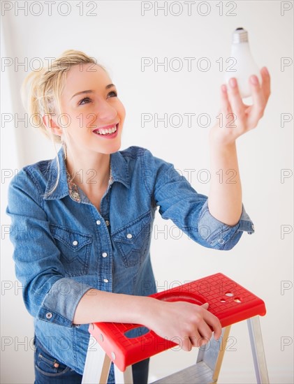 Young woman holding light bulb,  studio shot. Photo : Daniel Grill