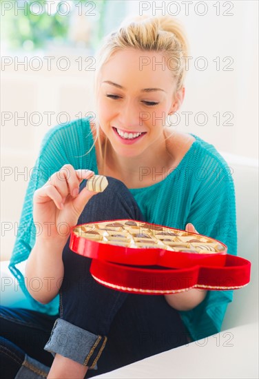 Smiling young woman eating chocolates. Photo : Daniel Grill