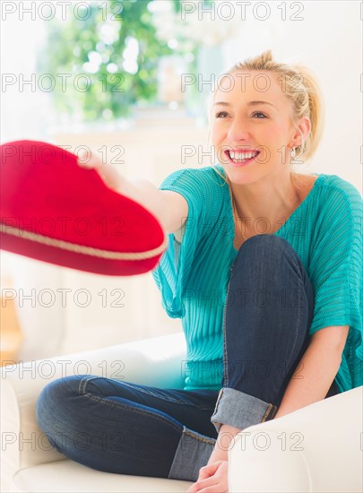 Smiling young woman holding box of chocolates in heart shape. Photo : Daniel Grill