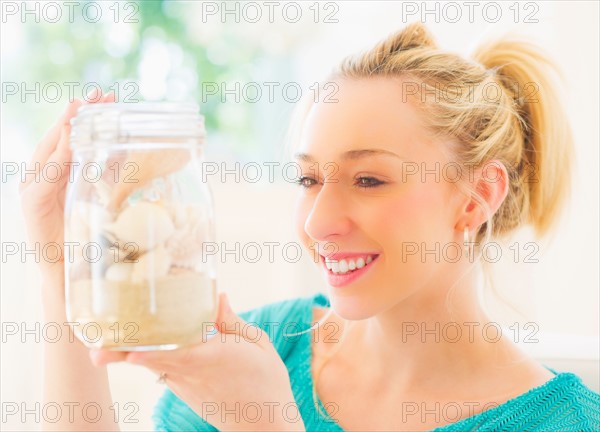 Young woman holding shells in jar. Photo : Daniel Grill