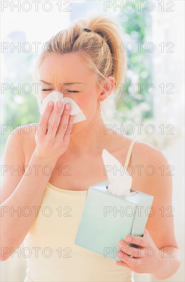 Young woman sneezing. Photo : Daniel Grill