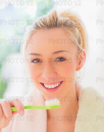 Portrait of smiling young woman with toothbrush. Photo : Daniel Grill