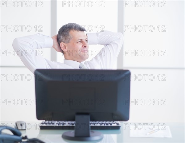 Portrait of businessman relaxing at desk. Photo : Daniel Grill