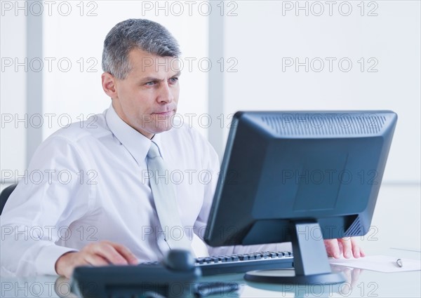 Portrait of businessman working at desk. Photo : Daniel Grill