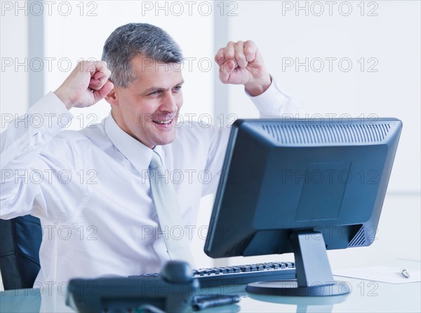 Portrait of happy businessman working at desk. Photo : Daniel Grill