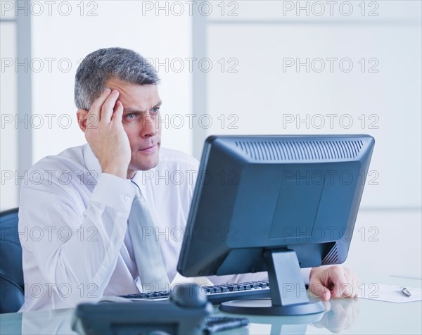 Portrait of worried businessman working at desk. Photo : Daniel Grill