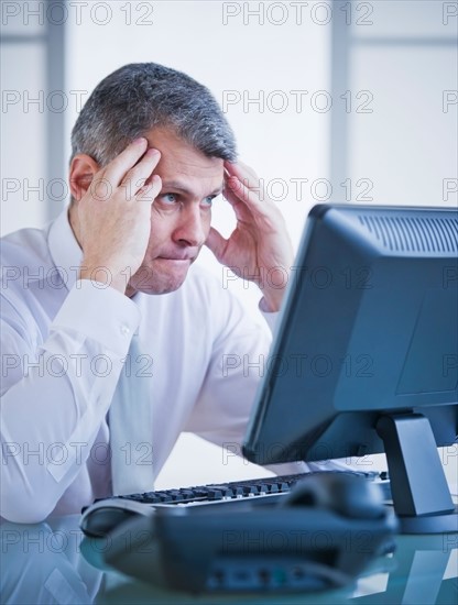 Portrait of worried businessman working at desk. Photo : Daniel Grill