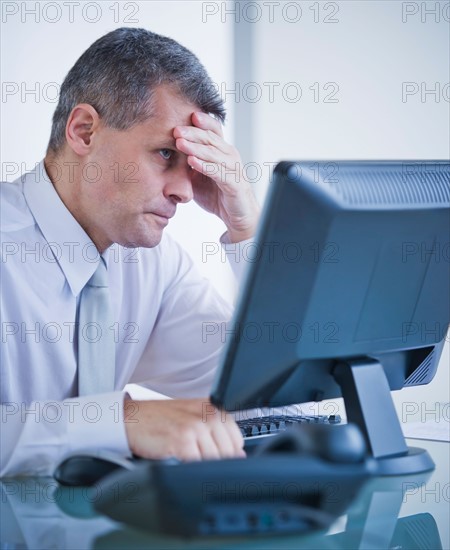 Portrait of worried businessman working at desk. Photo : Daniel Grill