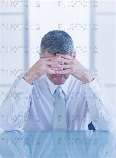 Portrait of depressed businessman sitting at desk. Photo : Daniel Grill