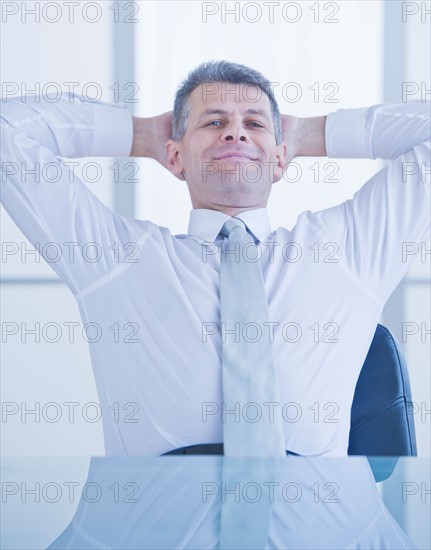 Portrait of businessman relaxing at desk. Photo : Daniel Grill