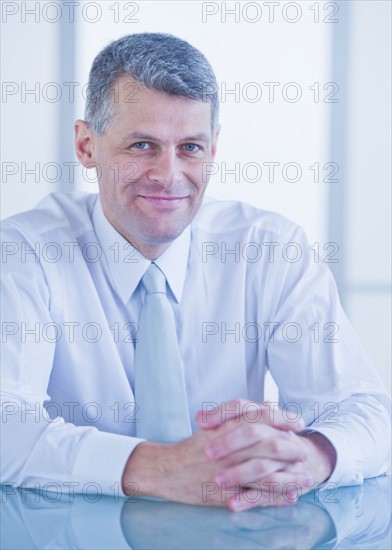 Portrait of businessman sitting at desk. Photo : Daniel Grill