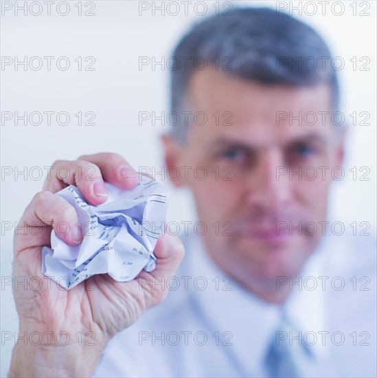 Man holding crumpled paper ball. Photo : Daniel Grill