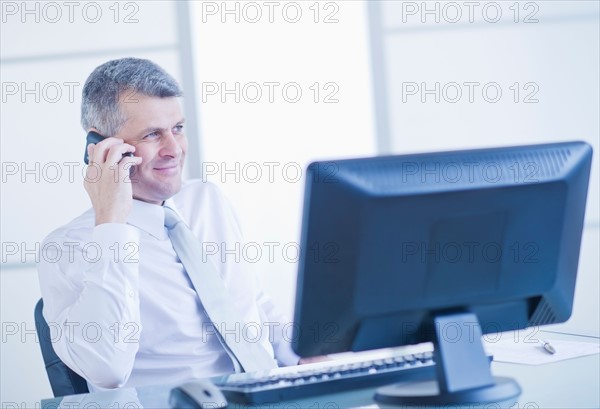 Man with mobile phone sitting in office. Photo : Daniel Grill