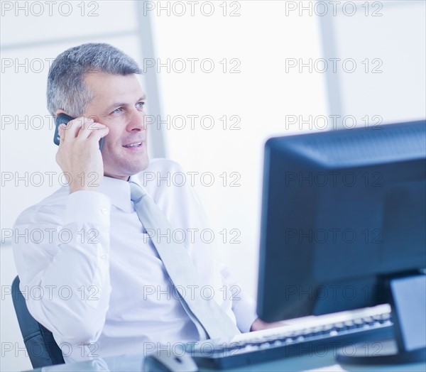 Man with mobile phone sitting in office. Photo : Daniel Grill